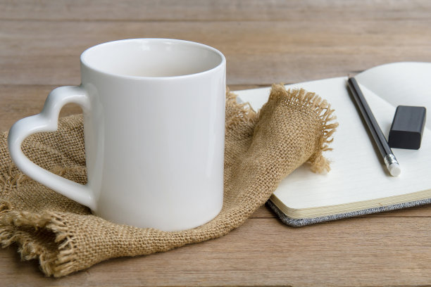 白杯咖啡，笔记本，铅笔和橡皮在桌子上。图片下载