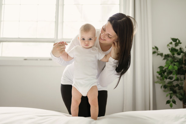 母亲和婴儿在家里的白色床上图片下载