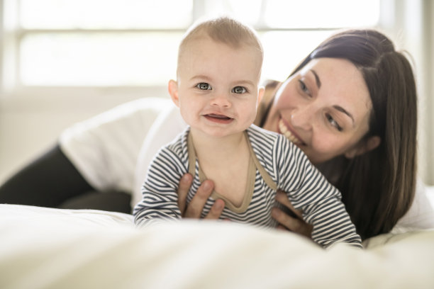 母亲和婴儿在家里的白色床上图片下载