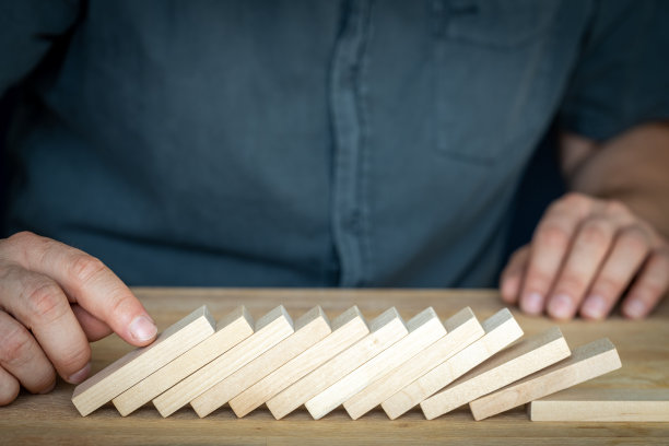 失败的商业交易，经济崩溃，市场危机，创意理念，糟糕的公司管理，一个商人站在像多米诺骨牌一样被推倒的木块上图片下载