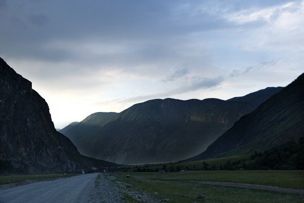 夏日，在阿尔泰广袤的山坡上，一条带状的道路蜿蜒而过图片下载