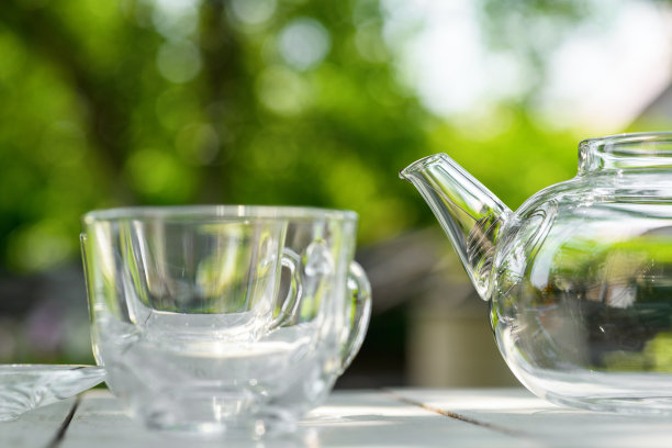 绿色背景上的空玻璃茶壶和杯子。下午茶时间图片下载