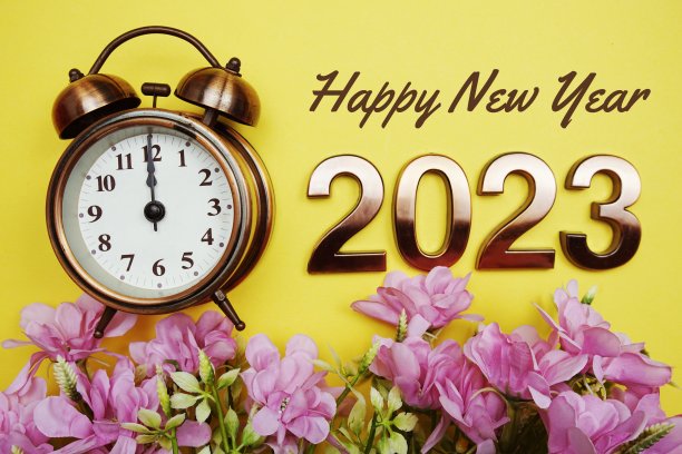 2023年新年快乐，黄色背景的闹钟和花朵装饰图片下载