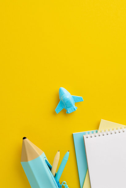 学校附件的概念。俯视图垂直照片的学校用品日记铅笔盒与钢笔和飞机形状的卷笔刀在孤立的黄色背景与copyspace图片下载