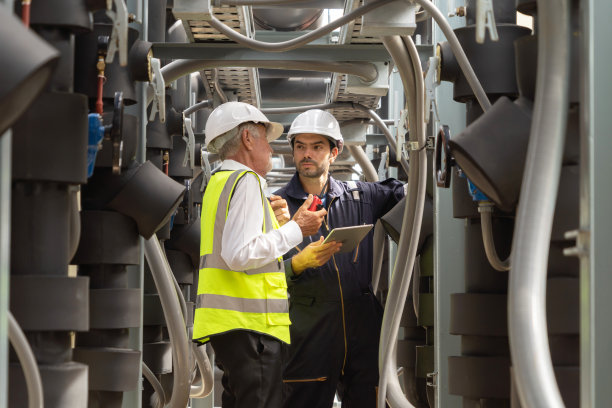 工程师或工人团队，在工业工厂工作的人。屋顶建筑上的冷却塔。系统工作的机器。冷凝器供水管路。通风式压缩机图片下载