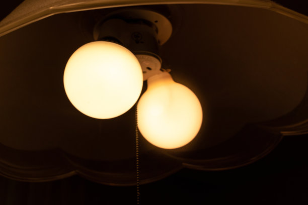 两个橙色的灯泡在黑暗的房间里发光图片下载