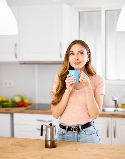 现代家庭厨房里一杯咖啡的时髦女人肖像图片下载