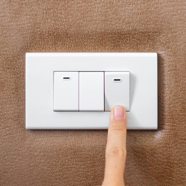 在家里用手指打开或关闭墙上的电灯开关。节能，电力，电气和生活方式的概念图片下载