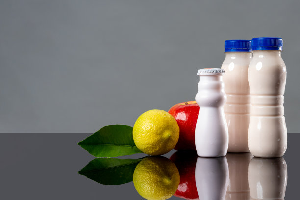 含有益生菌、双歧杆菌和维生素的乳制品。白色瓶装酸奶，苹果和柠檬作为益生菌产品的概念。双歧杆菌增加免疫力。益生菌促进消化。图片下载