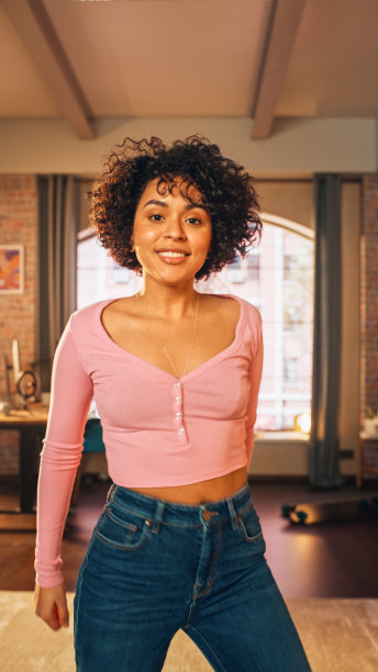 垂直屏幕:美丽的年轻黑人女性在智能手机上录制舞蹈视频，供社交媒体使用。时髦的拉丁女孩流她的舞蹈在互联网上从家里。图片下载