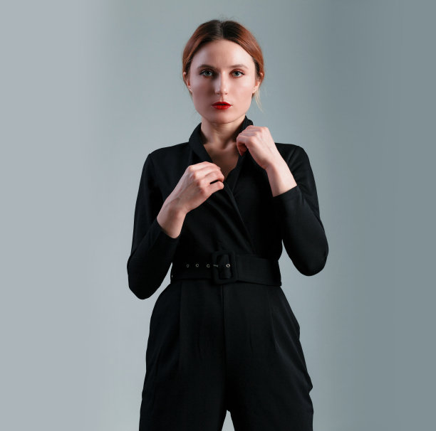 优雅的商业女性在灰色背景下穿着黑色经典连体裤。图片下载