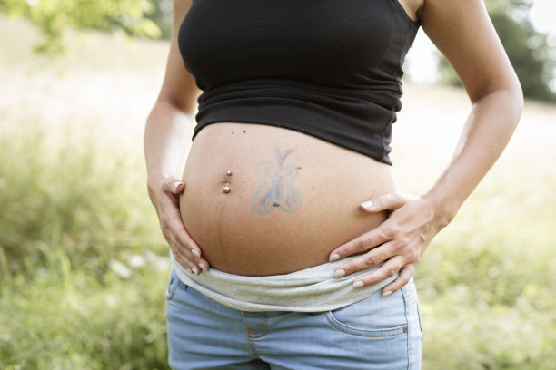 有胡子的男人在怀孕的女友肚子上画蝴蝶图片下载