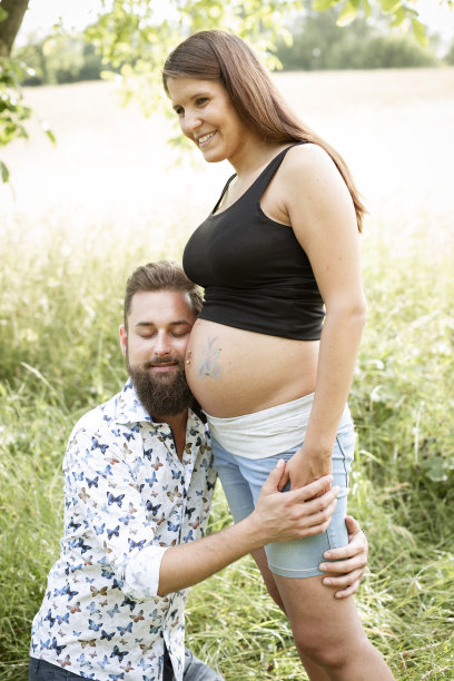 有胡子的男人在怀孕的女友肚子上画蝴蝶图片下载