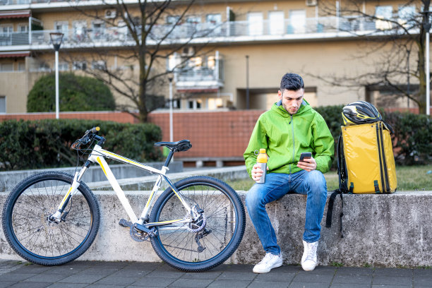 快递员休息，年轻骑手利用手机应用和城市地图搜索客户，生态快捷快递新业务图片下载