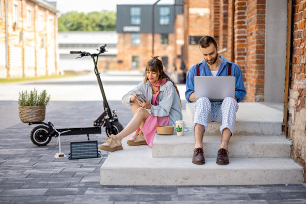 时髦的同事在户外用手机和笔记本电脑工作图片下载