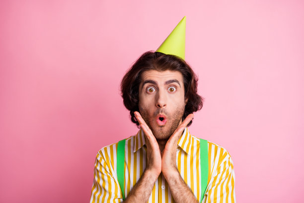 照片上的年轻人惊讶的震惊的惊讶戴派对帽子生日庆祝孤立在柔和的颜色背景图片下载