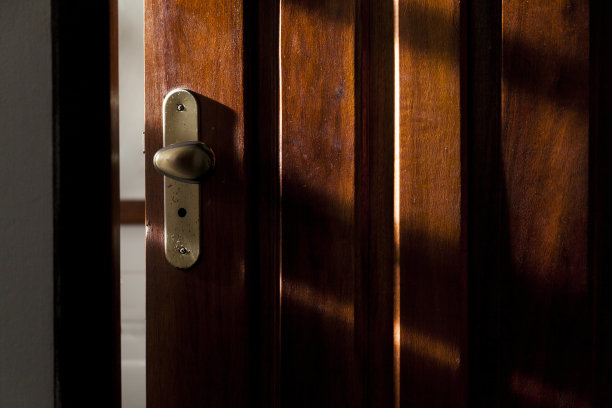 酒店房间门锁上有一缕阳光从侧面照射进来。图片下载