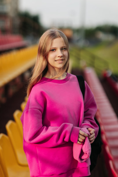 一个十几岁的学生看着相机的肖像，背景是学校的体育场图片下载