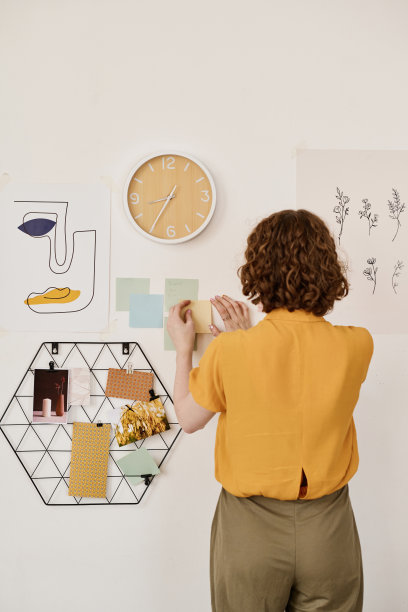 年轻的创意女性自由职业者在墙上贴便条的背影图片下载