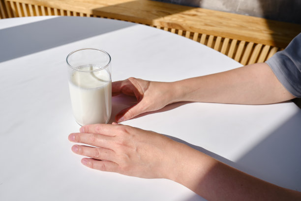 女孩手中的一杯牛奶饮料或酸奶。乳糖不耐症的概念。透明玻璃杯，牛奶可口图片下载