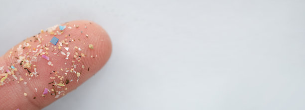 人类手指上的微型塑料颗粒作为尺度。水污染和全球变暖的概念。图片下载