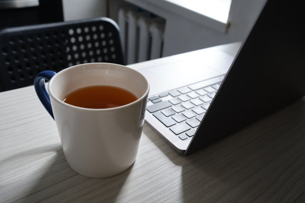 桌上有笔记本电脑和一杯热茶。工作氛围。现代通讯手段。在一个白色做旧的桌面图片下载