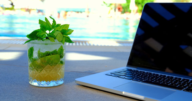 一张笔记本电脑和鸡尾酒在泳池边的照片图片下载