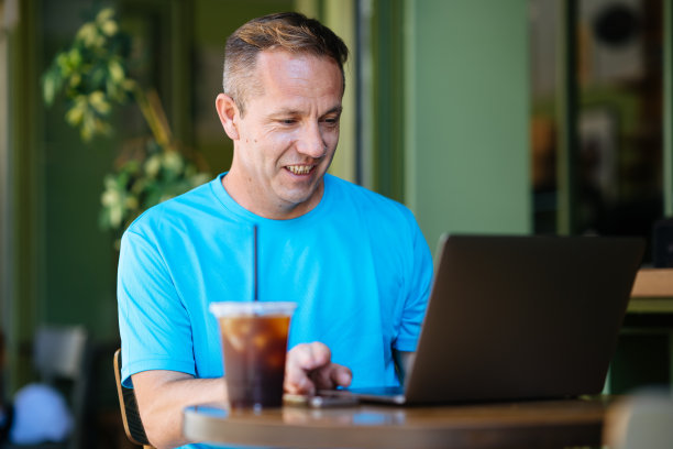 一个年轻人在咖啡店里用笔记本电脑。图片下载