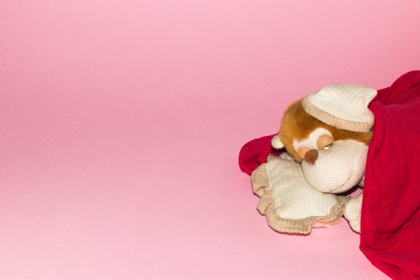 依偎着睡觉的猴子玩具右侧粉红色的背景，复制空间，肌肉艺术设计，慵懒的日子，甜蜜的梦想图片下载