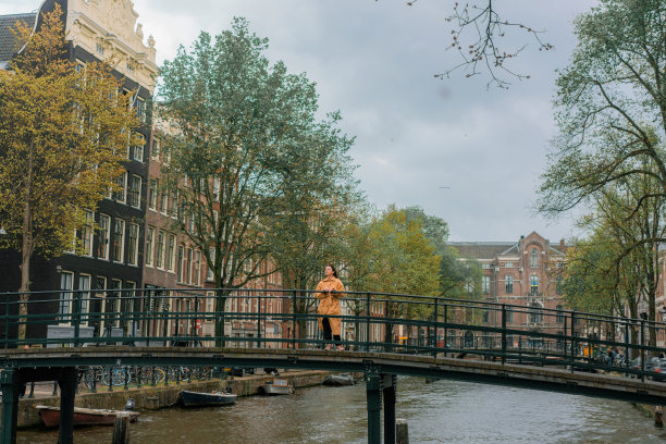 日落时分，女子站在阿姆斯特丹运河的桥上图片下载