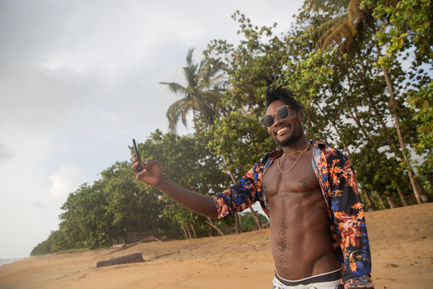 一名迷人的男子在非洲热带海滩度假时自拍。图片下载