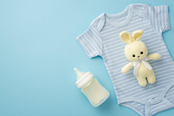 小配件的概念。俯视图照片针织兔玩具蓝色紧身衣和奶瓶上孤立粉彩蓝色背景与copyspace图片下载