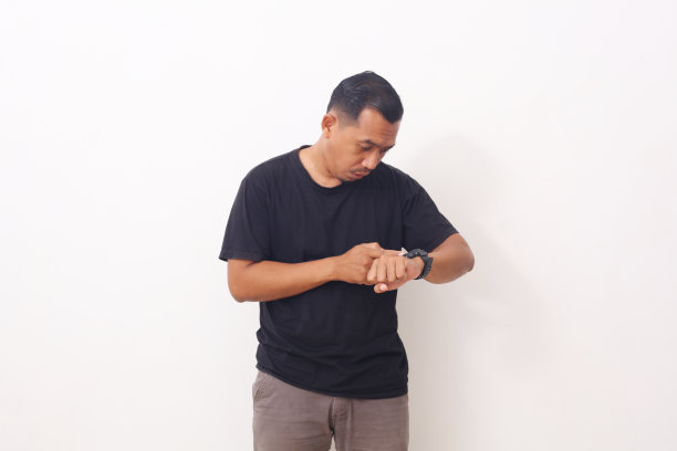 年轻的亚洲人担心时间看他的手表。时间期限的概念图片下载