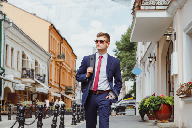 年轻英俊的男人，穿着西装，戴着墨镜，背着双肩包图片下载