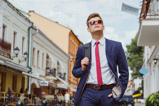 年轻英俊的男人，穿着西装，戴着墨镜，背着双肩包图片下载