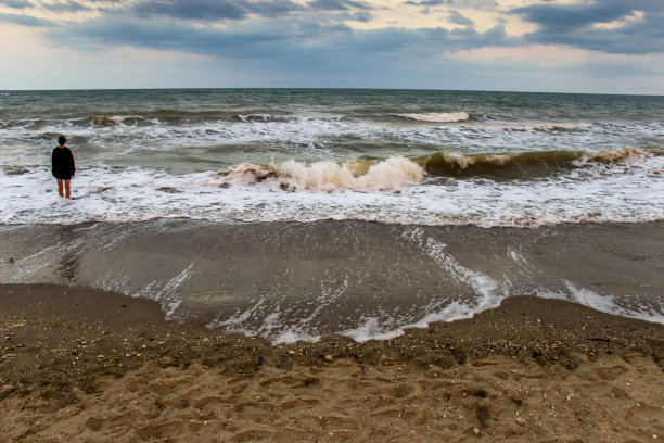 十几岁的女孩呆在傍晚的暴风雨大海，亚速海，乌克兰图片下载