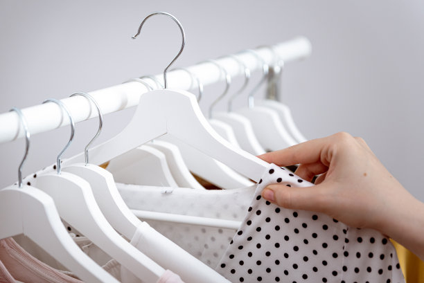 在时装店的衣架上，女人用手挑选要买的衣服，特写。图片下载