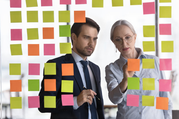 办公室职员在贴在墙上的便利贴上写字图片下载