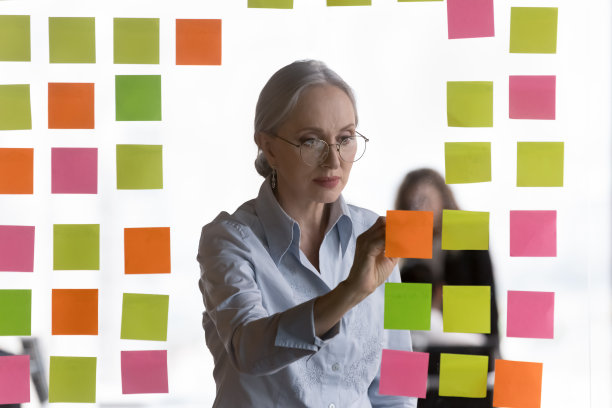 专注的中年女商人在便签纸上做笔记图片下载