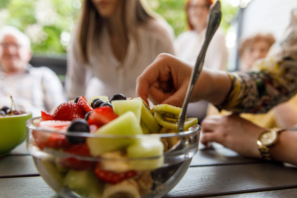 一个女人从桌子上的碗里拿着一块水果图片下载