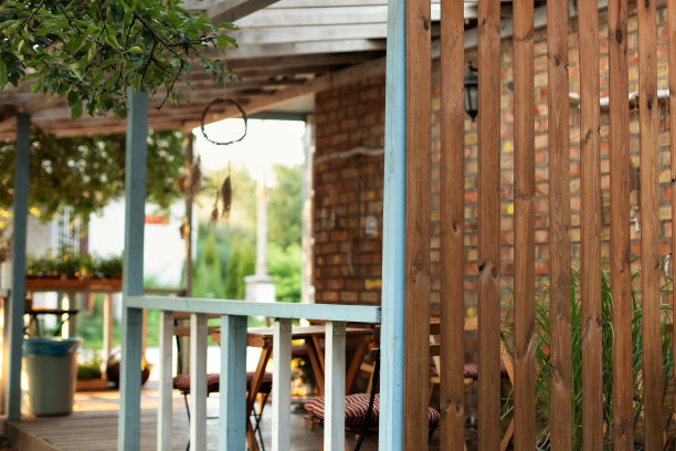 在夏日阳光明媚的日子里，带木制室外露台的立面住宅。带阳台和花园的外墙小屋。室内舒适的露台或阳台空间，可在室外后院放松身心。图片下载