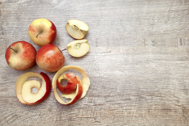 靠近红绿色的整个和切片苹果和果皮在木制桌子上的复制空间的文本。新鲜水果背景，成熟切夏水果概念图片下载