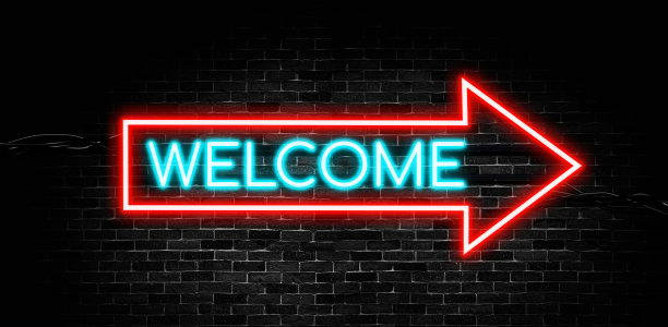 欢迎霓虹灯横幅与箭头形状的砖墙背景。图片下载