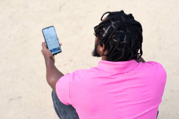 一名黑人男子手持智能手机的身后肖像图片下载