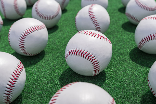 绿色地毯上一排新棒球的低角度视图图片下载
