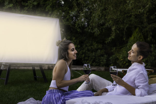 年轻可爱的情侣有一个约会在花园里的一杯酒，而在夏天的户外看电影图片下载