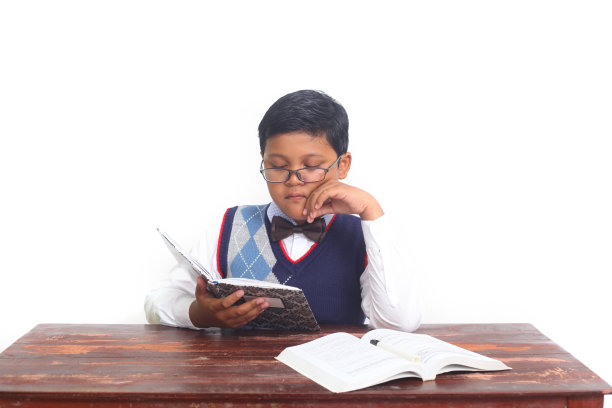 亚洲男生坐在那里看书。孤立在白色背景上图片下载