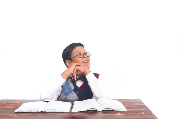 亚洲小男孩在白色背景下思考和阅读一本书图片下载