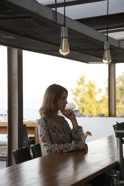 一个悲伤严肃的女人在吧台喝鸡尾酒的侧面图片下载