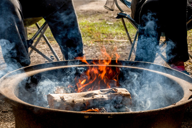篝火在火坑中燃烧。人坐着。露营生活。户外娱乐。图片下载